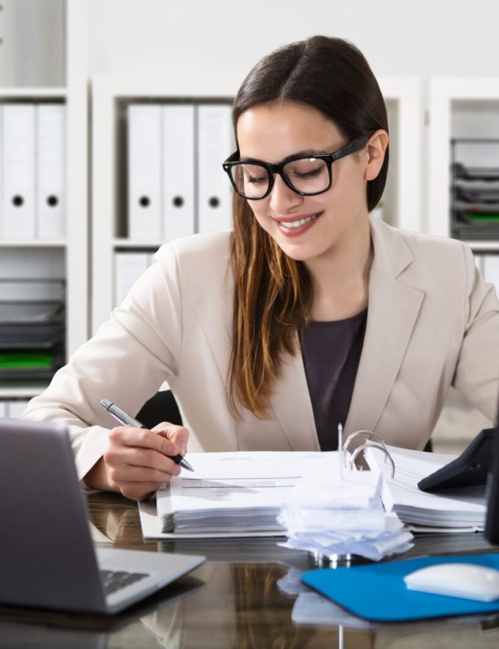 Happy Young Businesswoman Using Calculator At Workplace